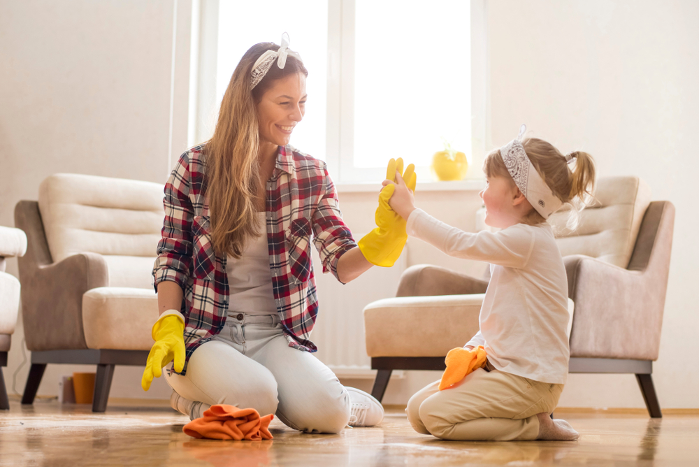 Mom and daughter high-fiving while cleaning the wood floor.